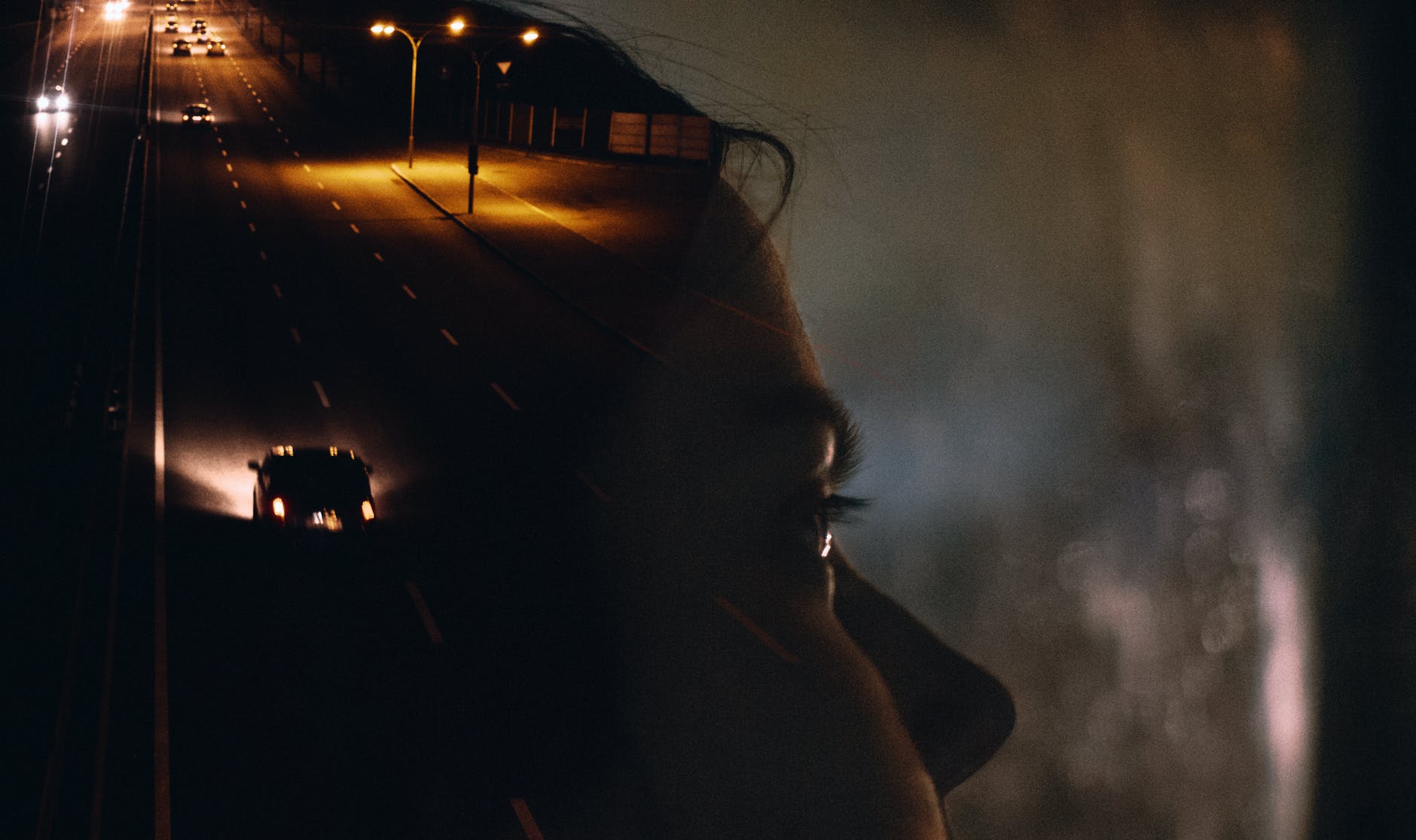 woman in car with road reflection on window at night